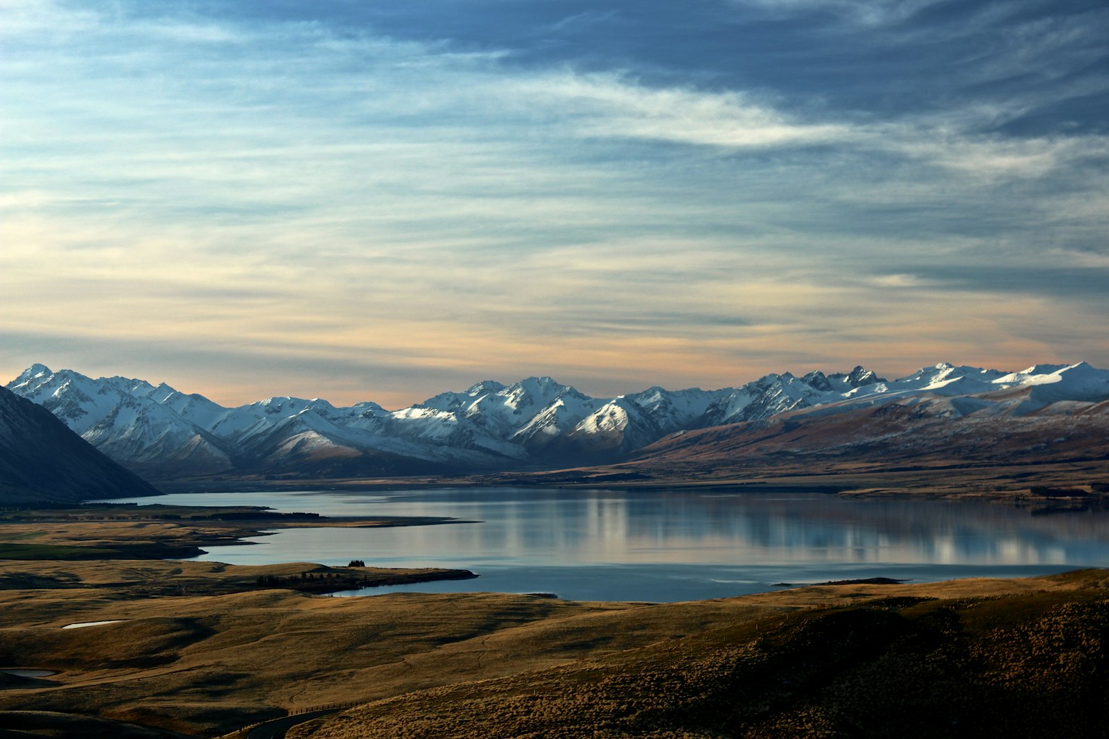 Alpine lake below snowy peaks at dusk