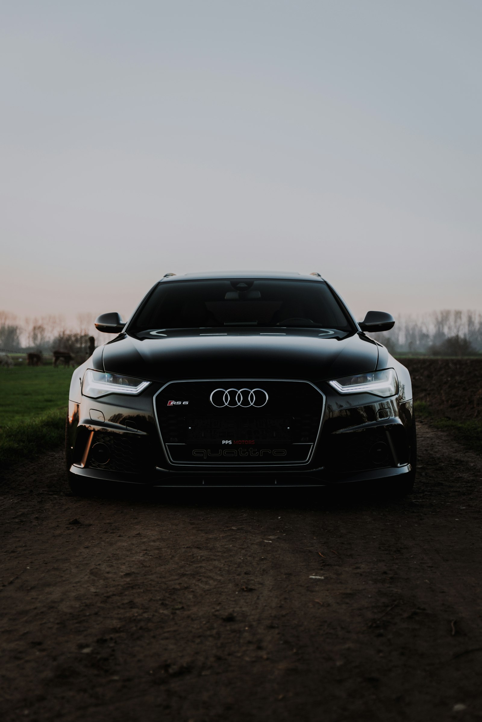Black performance wagon on a dirt track at dusk