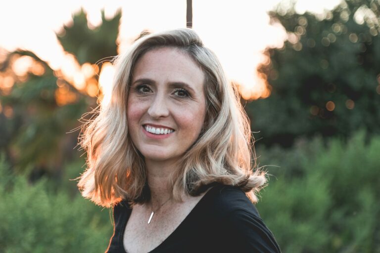 Smiling blonde woman outdoors at golden sunset