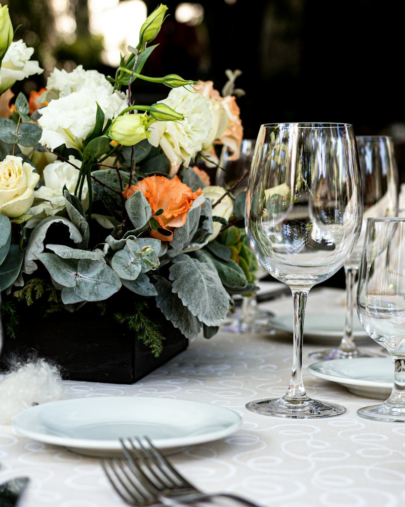 Orange and cream roses with dusty miller in a centrepiece on a set table