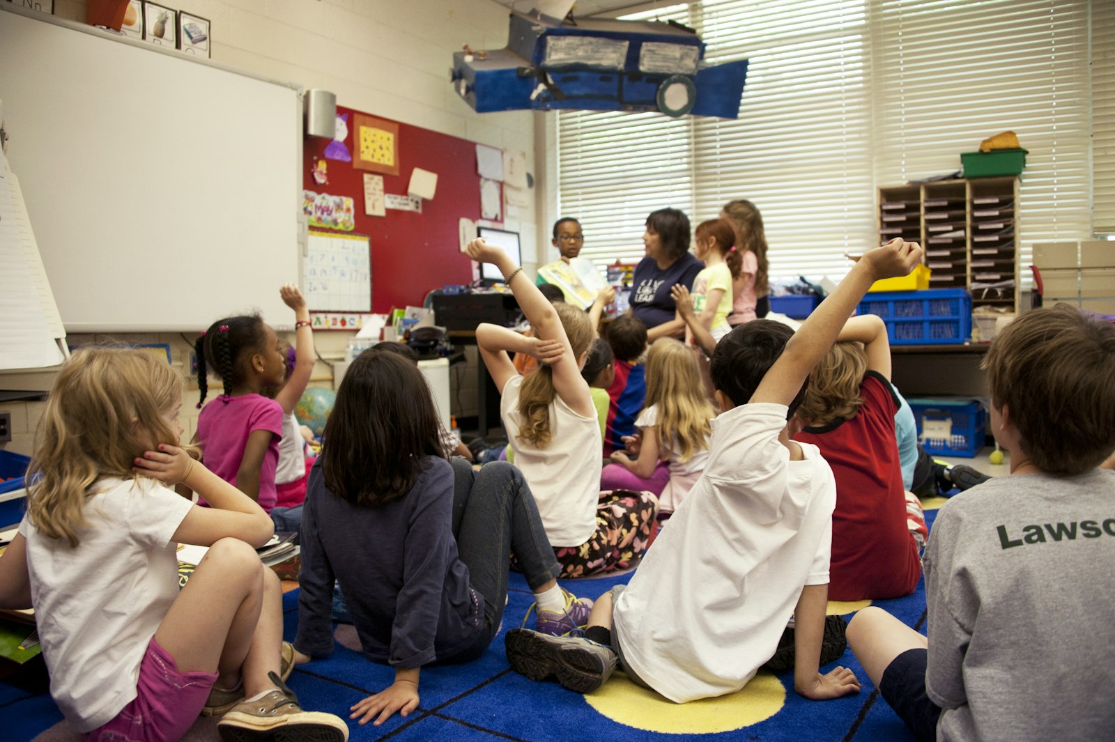 Classroom of children with their hands raised