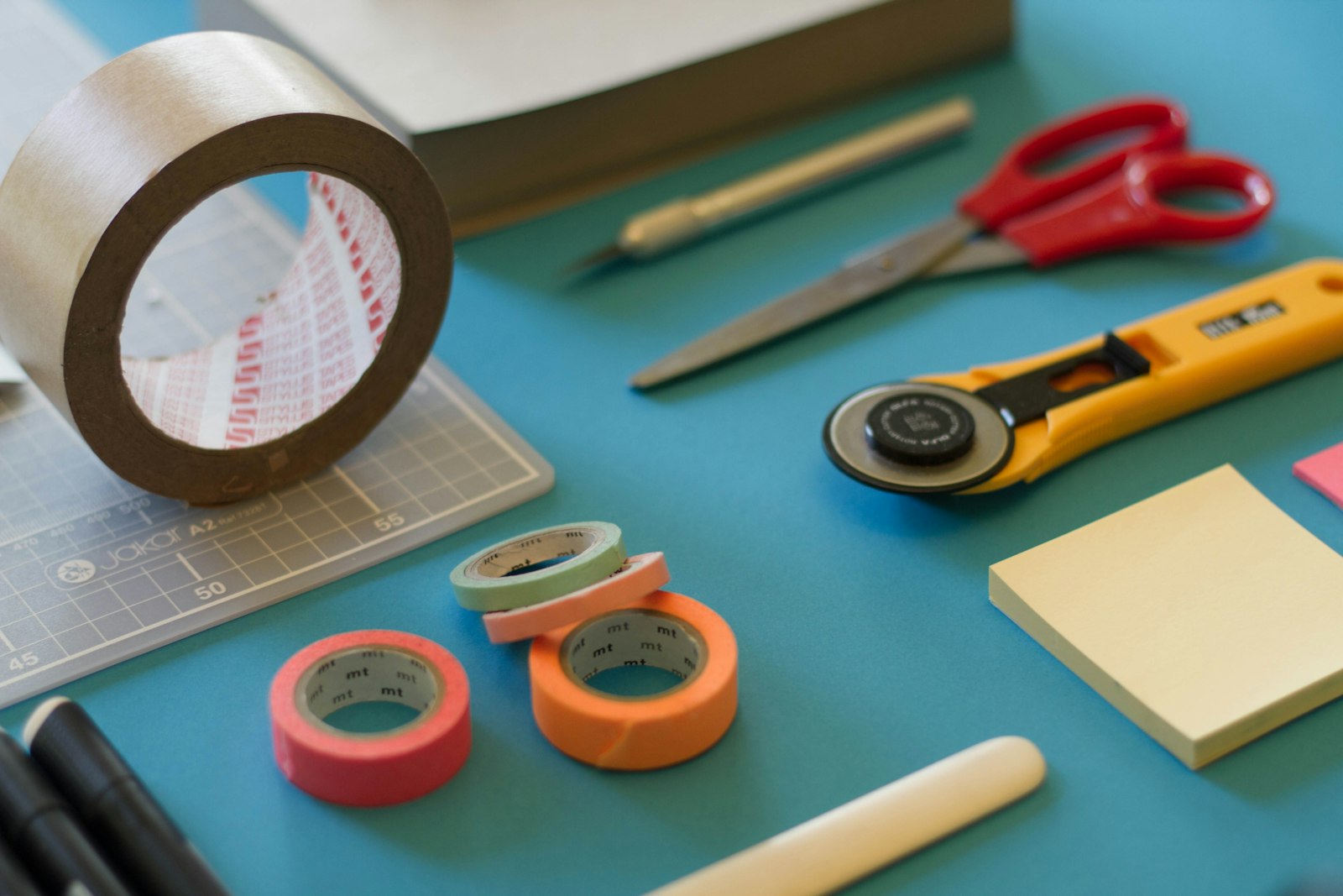 Craft tools and coloured tape on a teal desk