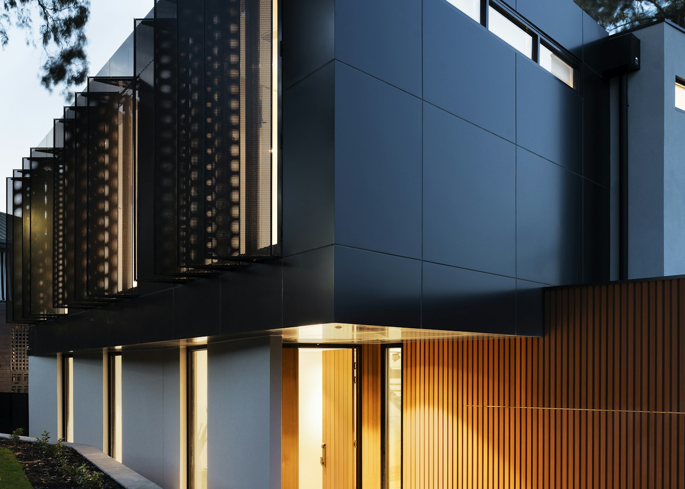 Dark clad modern house with lit timber entry