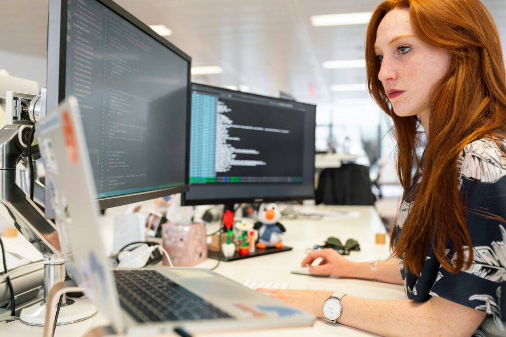 Developer at a desk working on a dual-monitor code setup
