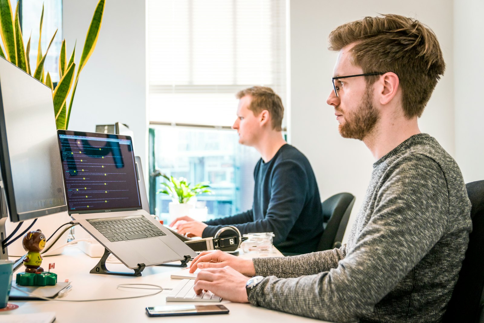 Two men working at monitors in bright office