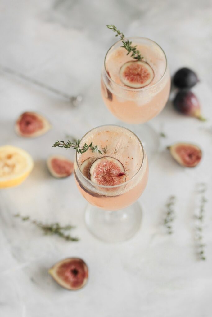 Two pink cocktails garnished with fig slices
