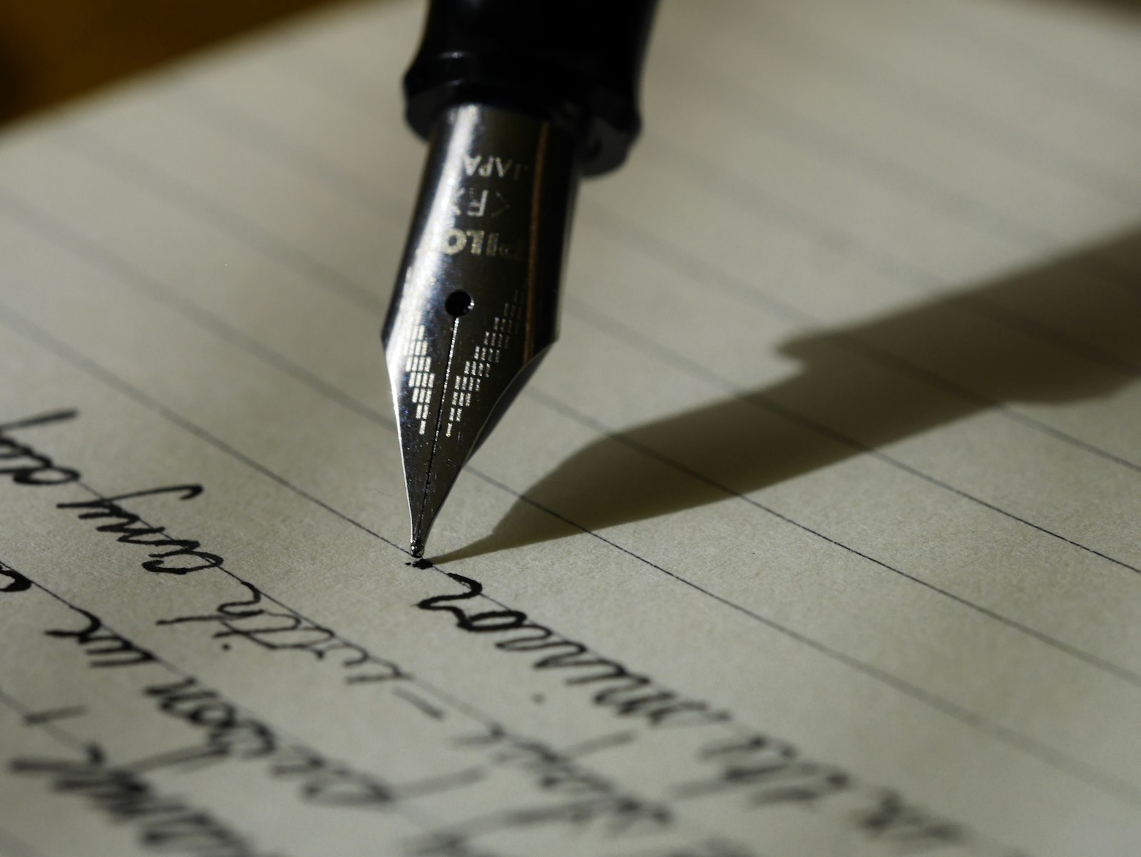 Fountain pen nib writing cursive on lined paper