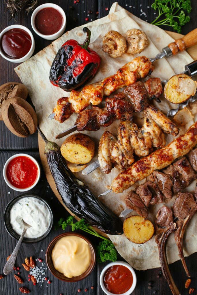 Grilled meat skewers and vegetables with dipping sauces