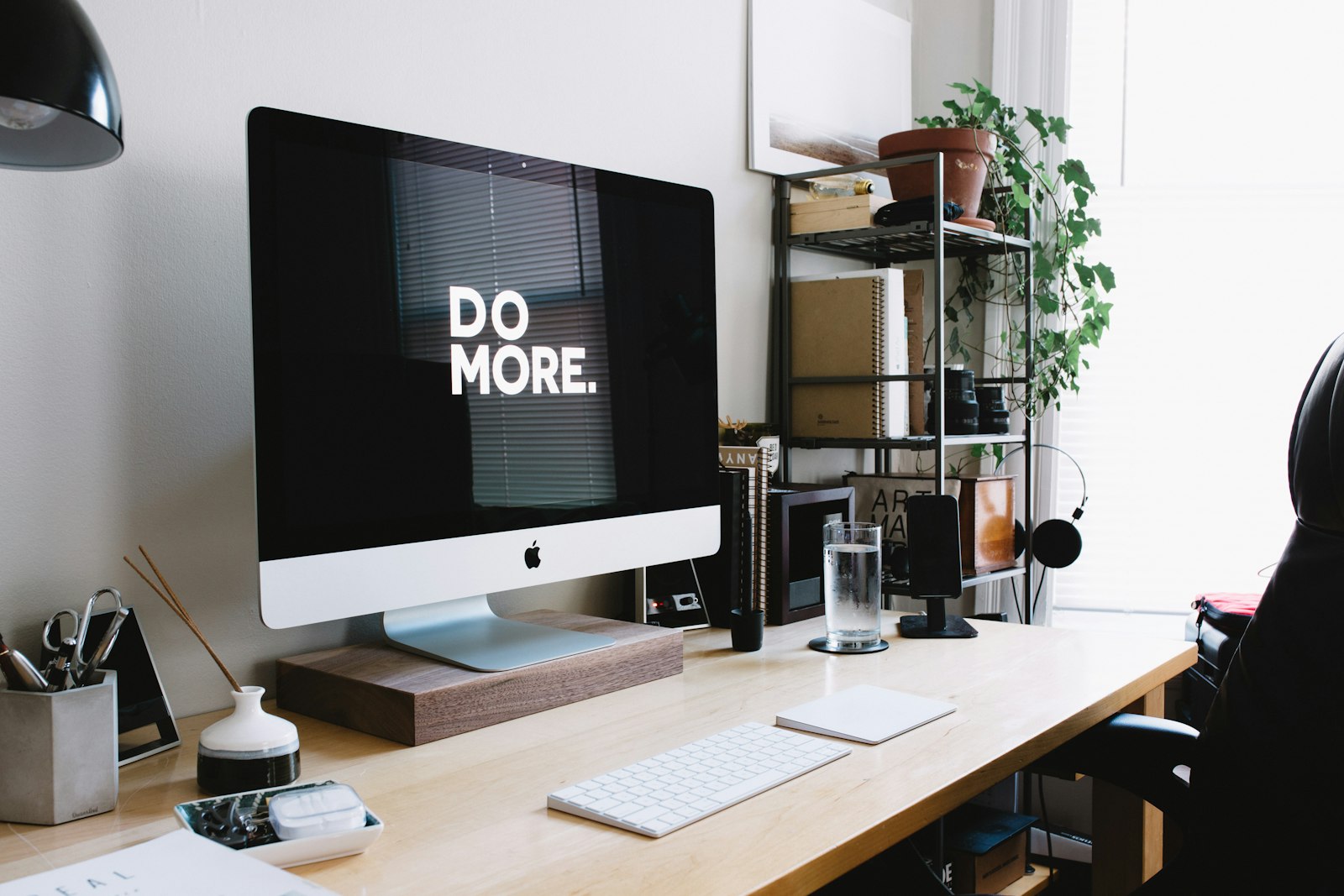 iMac on a wooden desk beside plants