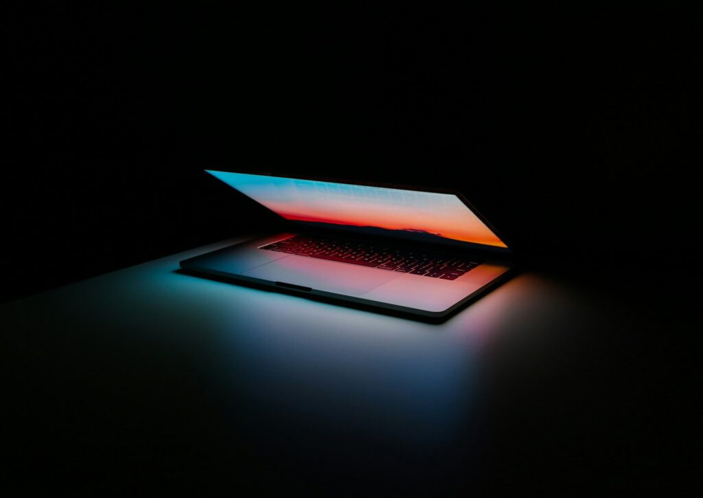 Half-open laptop glowing in a dark room
