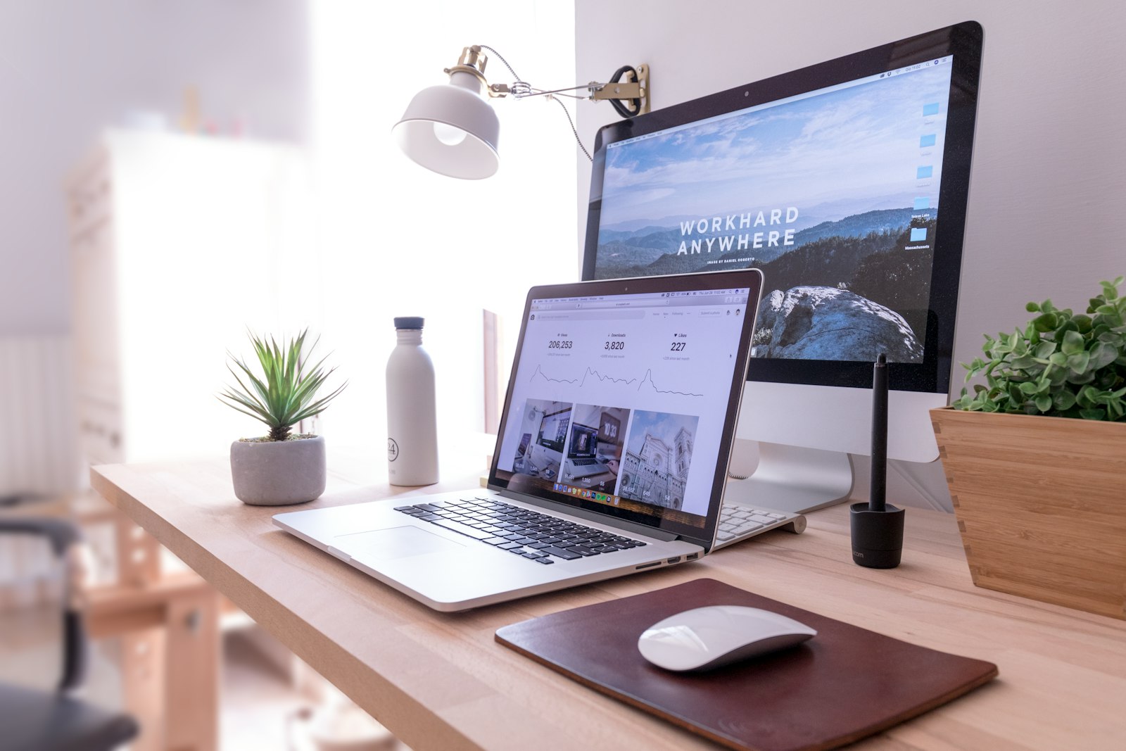 Laptop and monitor on a sunlit wooden desk