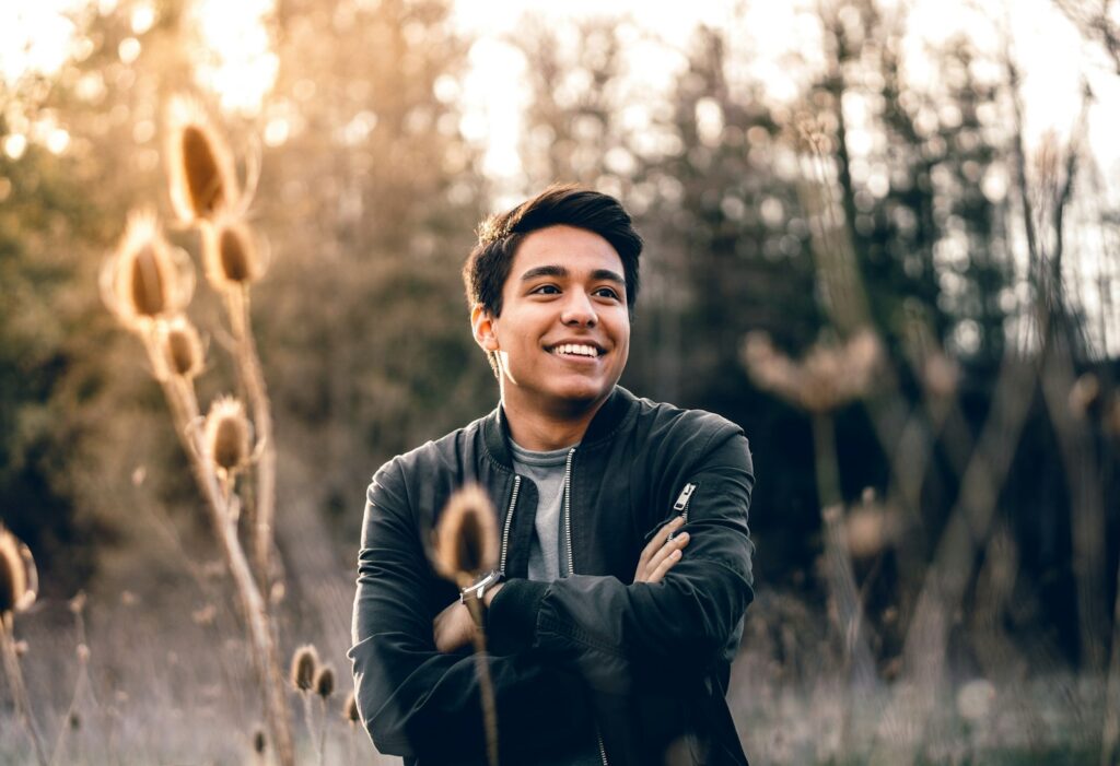 Smiling young man with folded arms outdoors