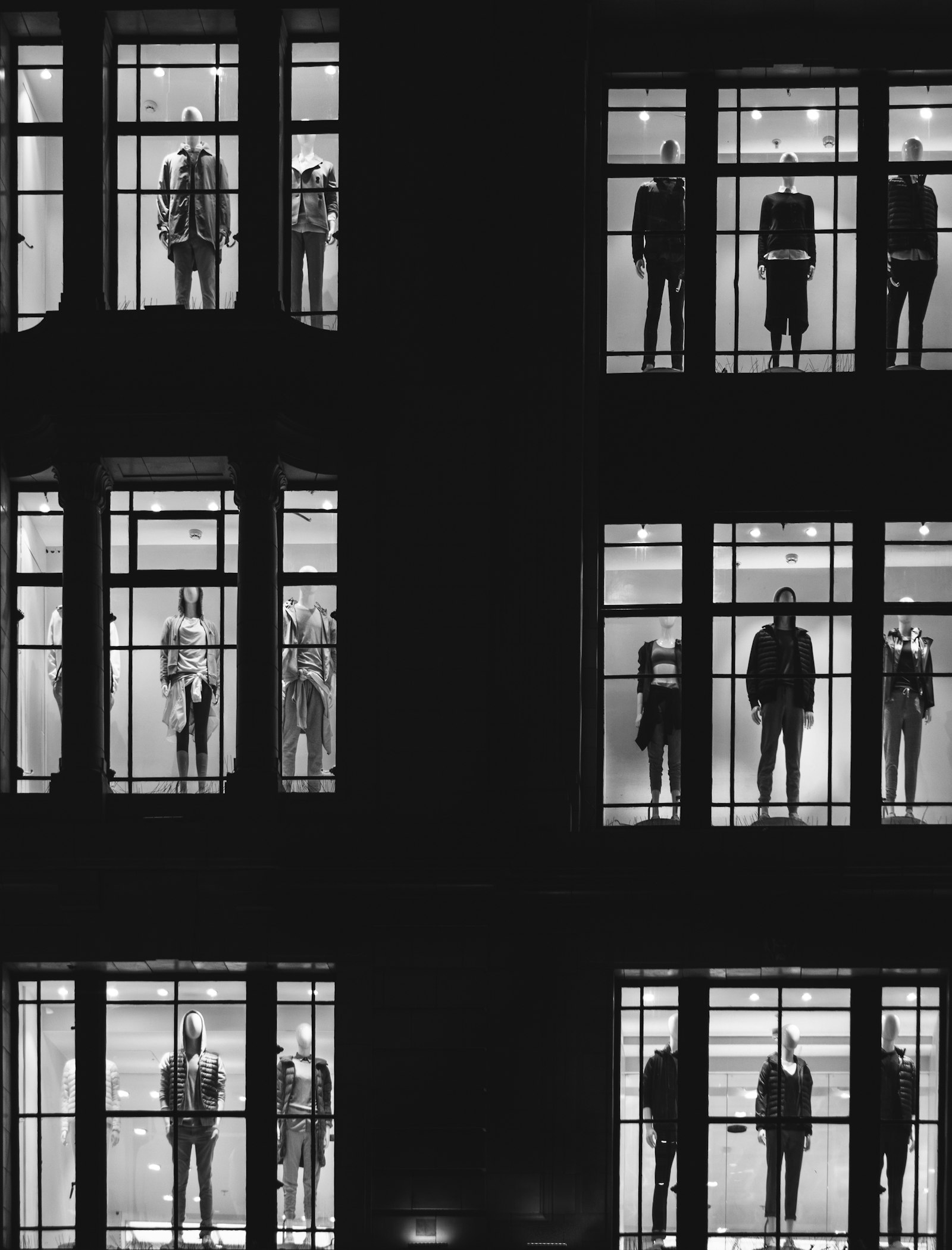 Lit store windows with mannequins in a dark facade
