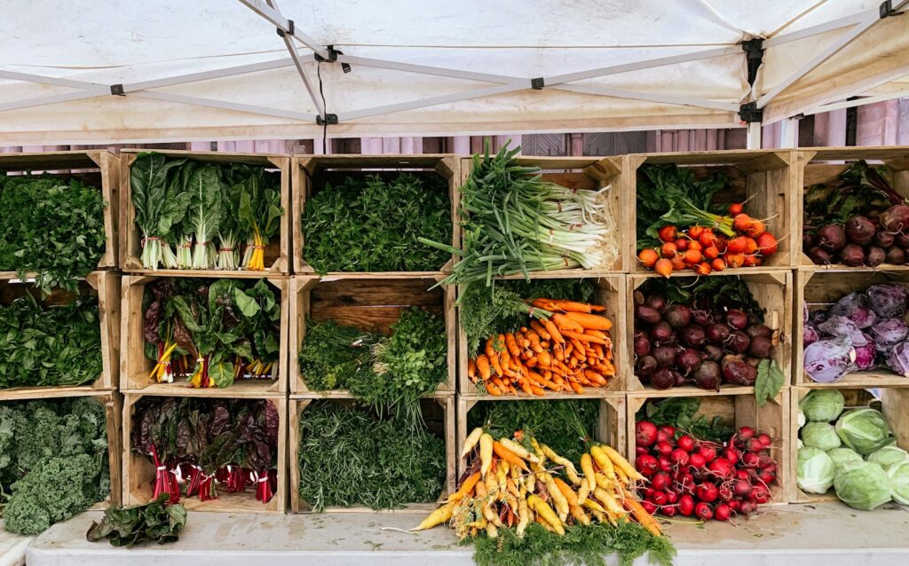 Farm stand of wooden crates filled with chard, carrots, beets and radishes