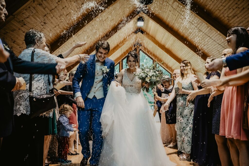 Bride and groom leaving through a timber porch as guests throw rice