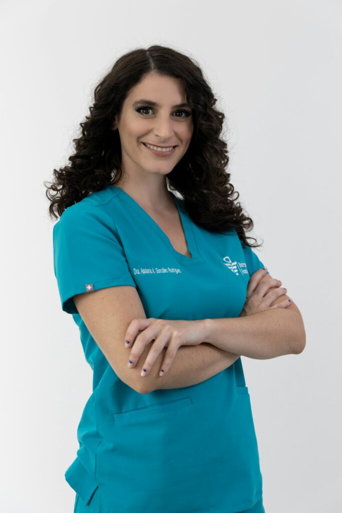 Smiling woman in teal scrubs with arms crossed