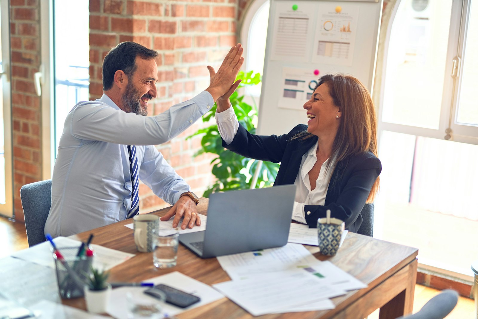 Colleagues high-fiving over a laptop in an office