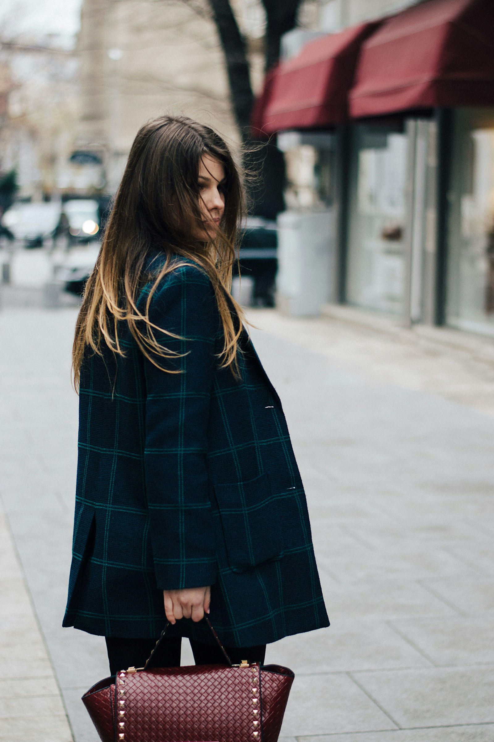 Woman in green plaid coat on a sidewalk