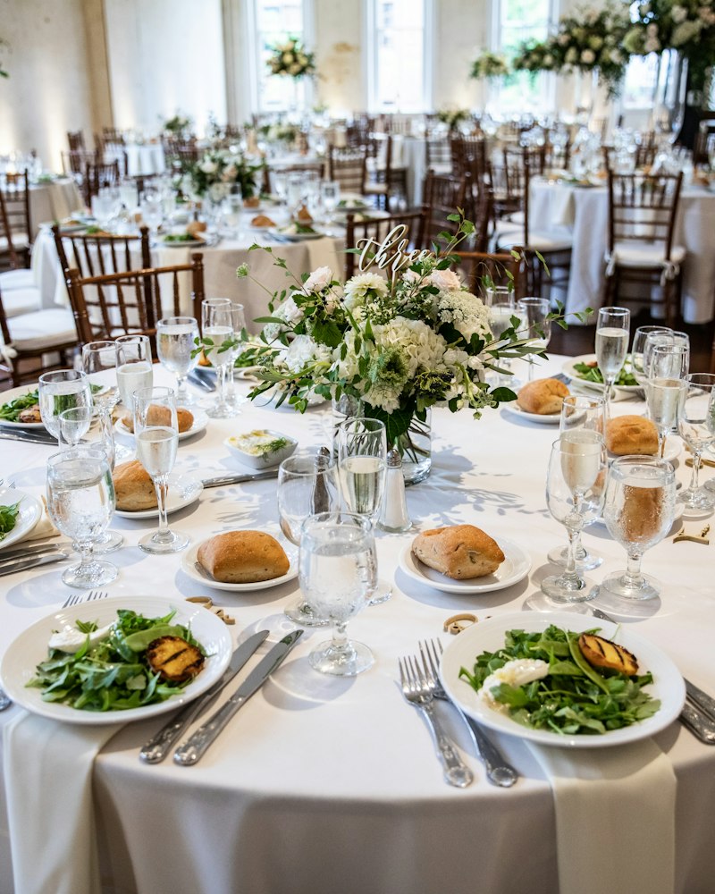 Round reception tables in white linen with greenery and white centrepieces