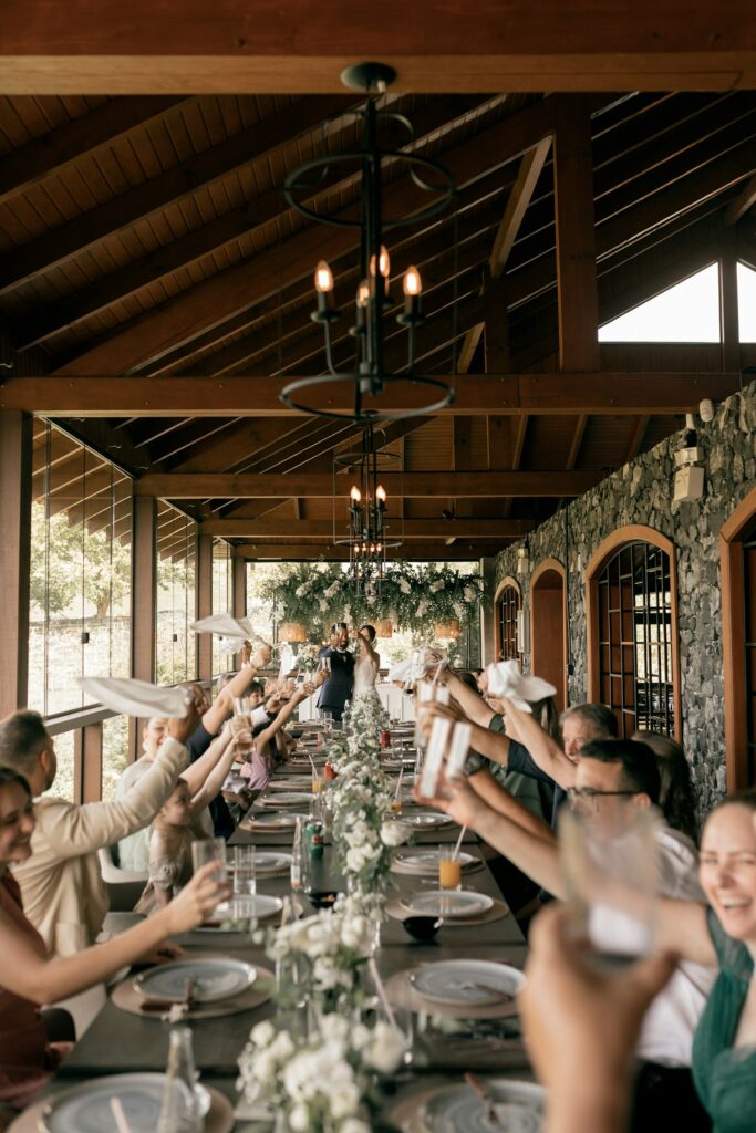 Guests raising a toast around a long table under a timber pavilion