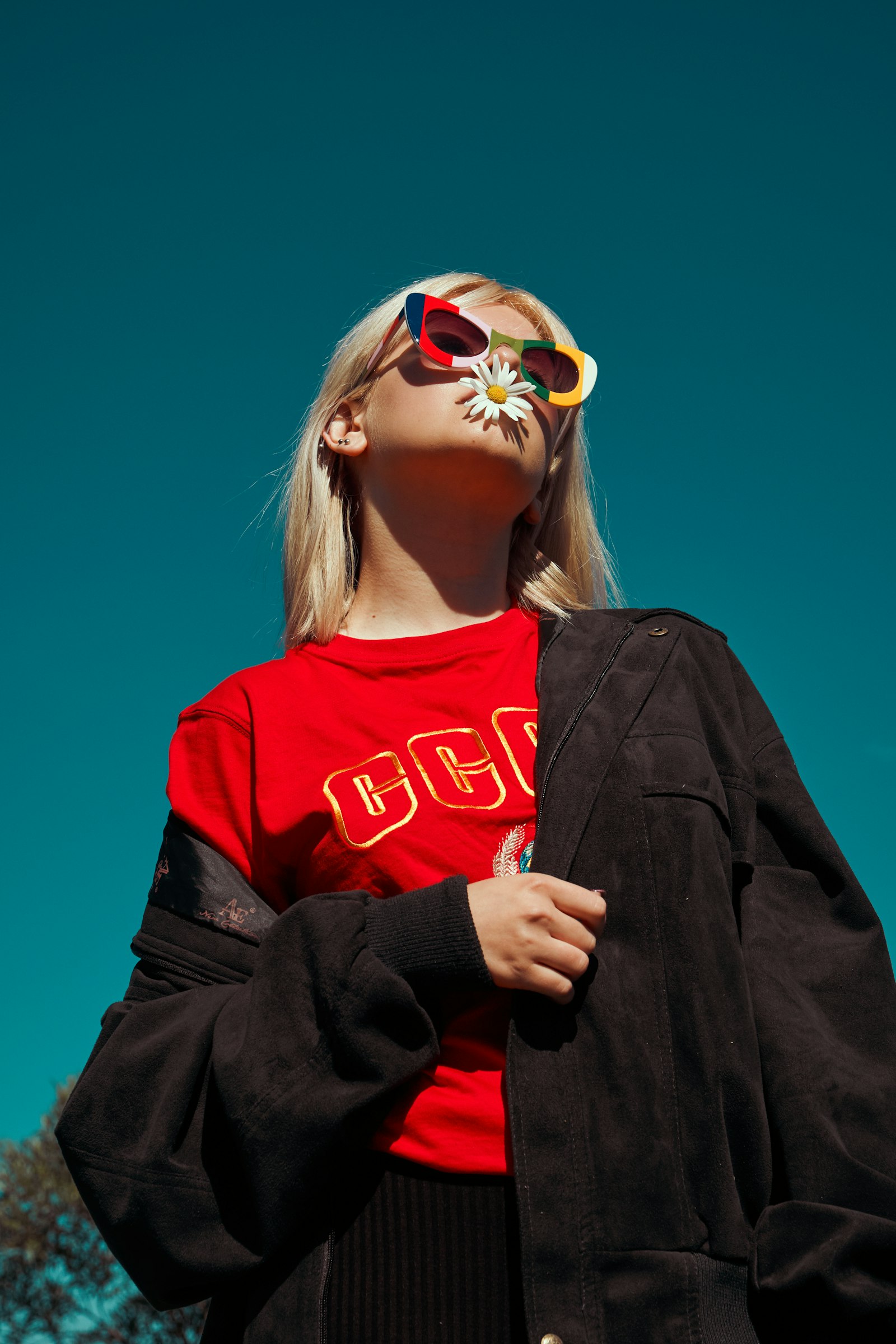 Woman in red tee and sunglasses against blue sky