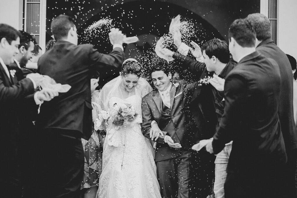 Guests showering the laughing newlyweds with rice, in monochrome