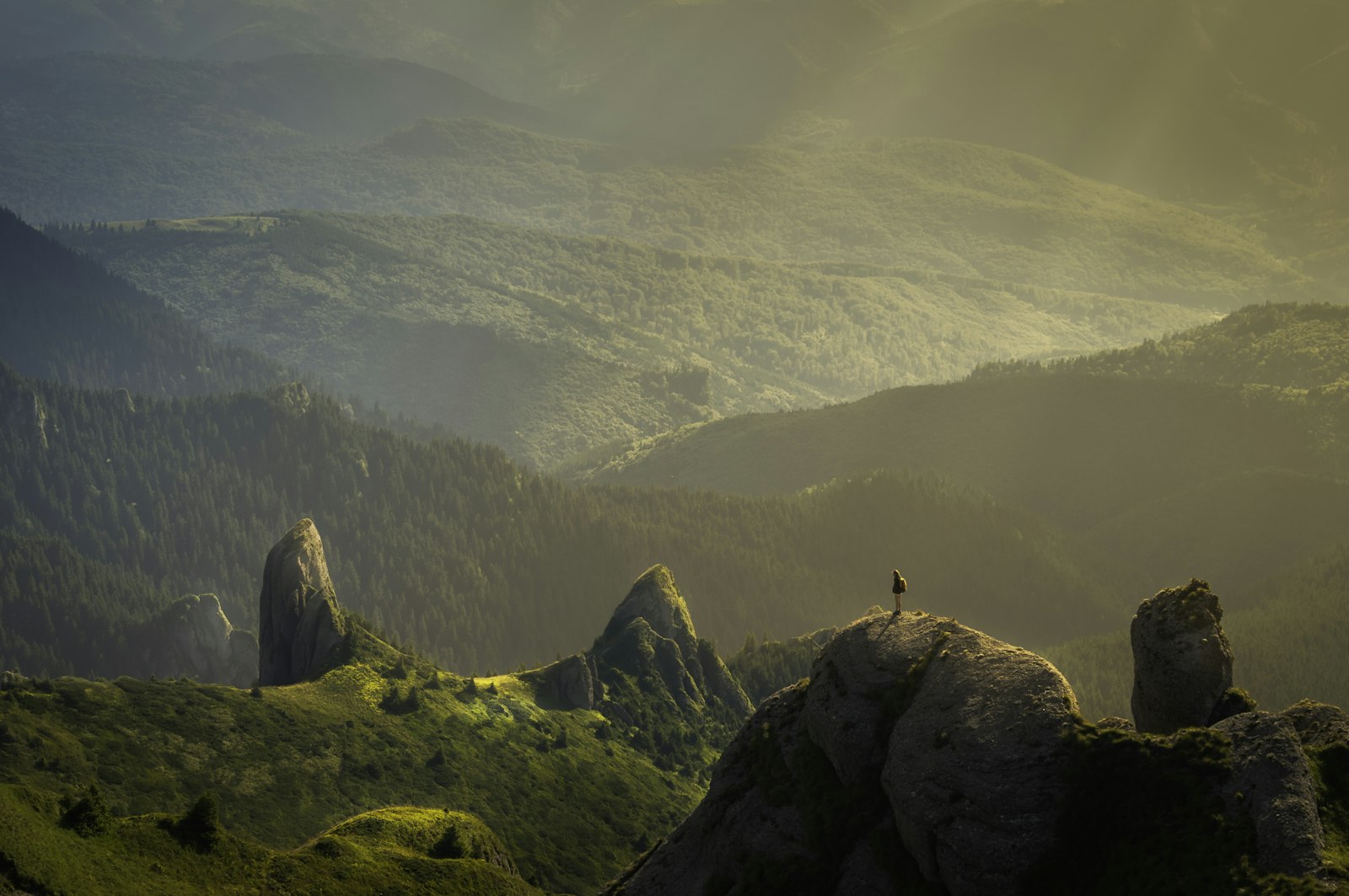 Lone figure on a rock above misty hills