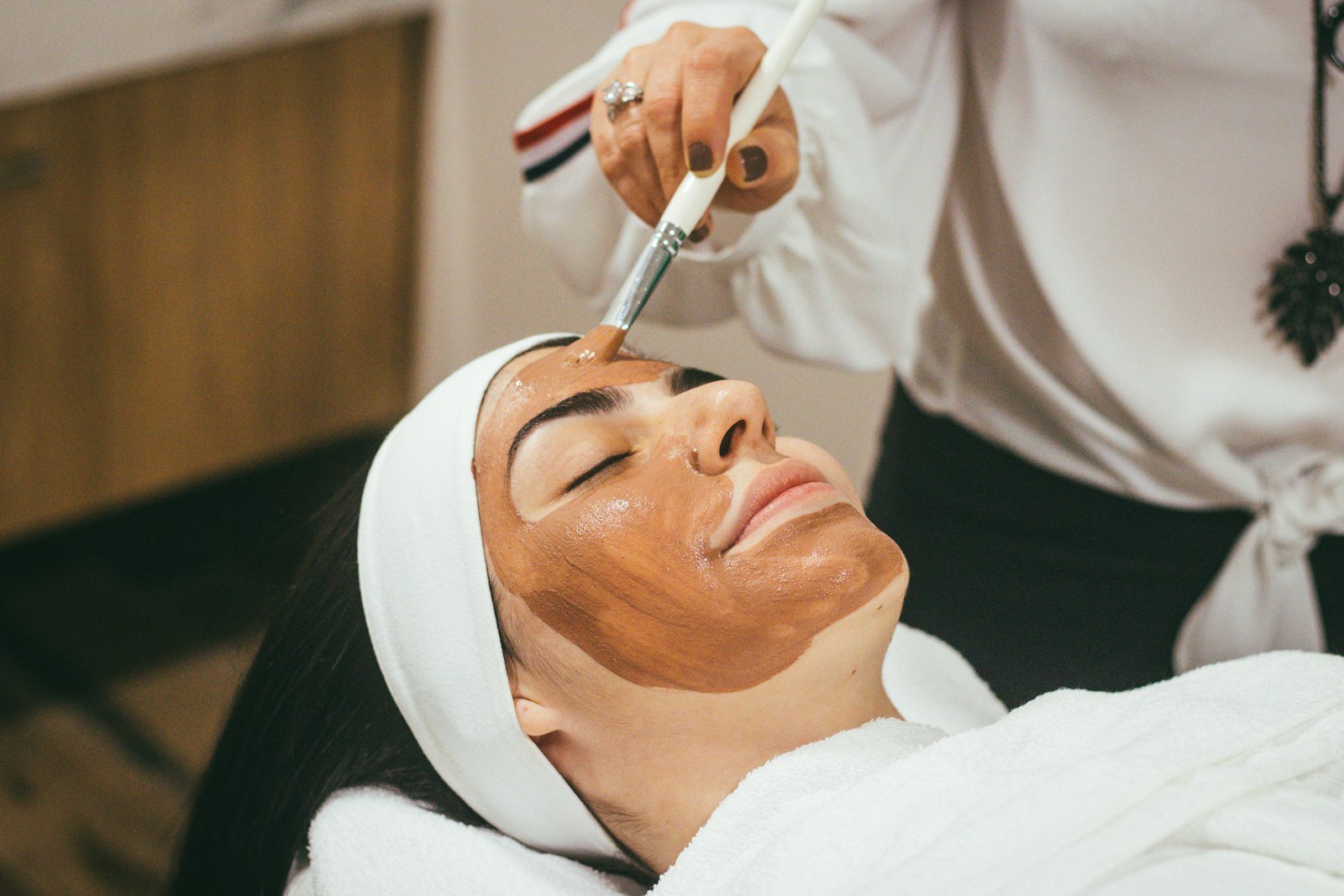 Clay face mask being brushed onto a woman at a spa