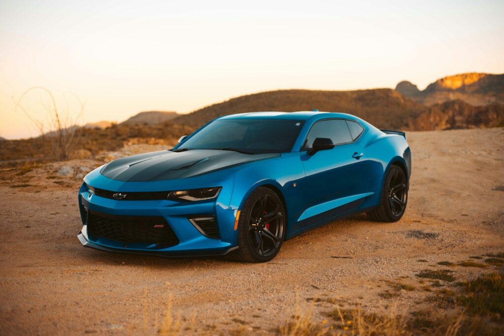 Blue sports coupe parked on desert dirt at golden hour