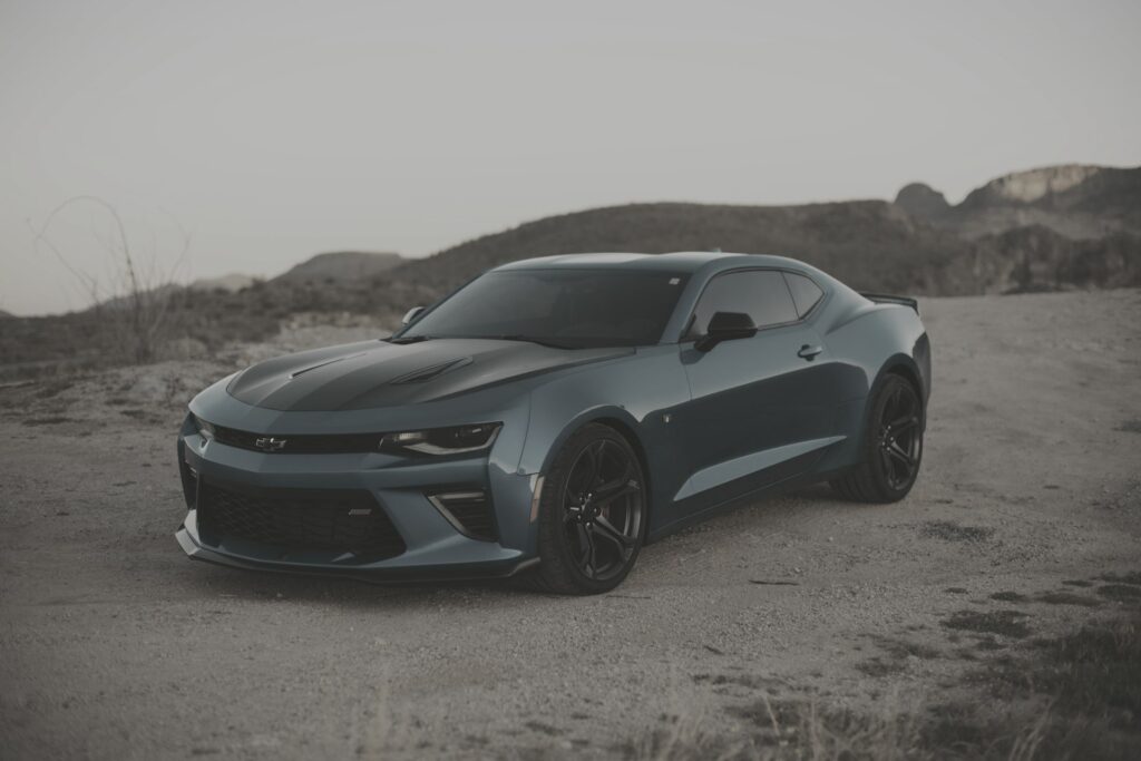 Blue sports coupe parked on desert dirt at golden hour