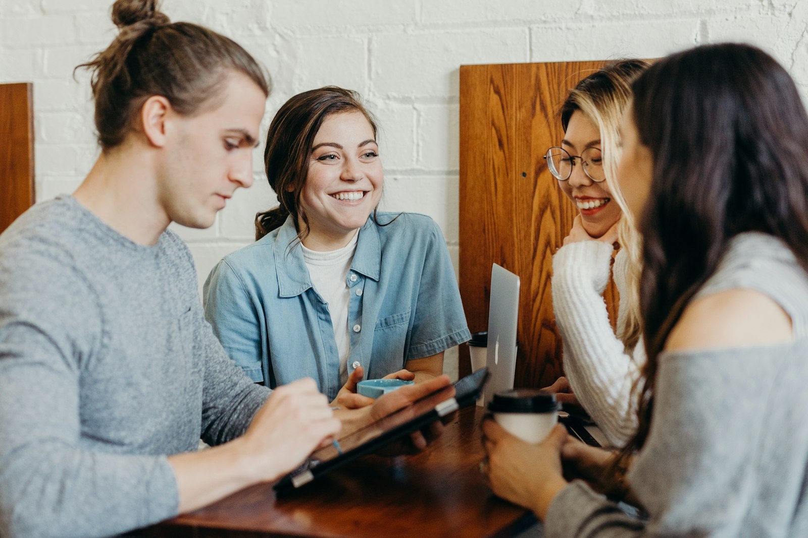 Students laughing around a cafe table with a laptop
