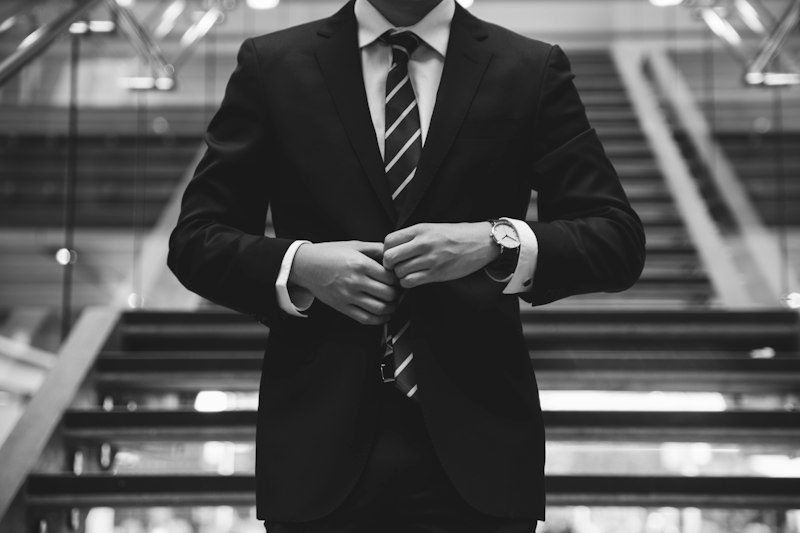 Man in a navy suit buttoning his jacket on a staircase