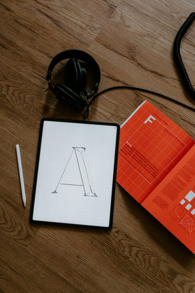 Tablet with sketched letter, headphones and orange magazine