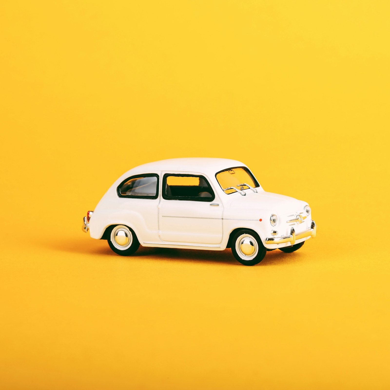 White toy car on a yellow background