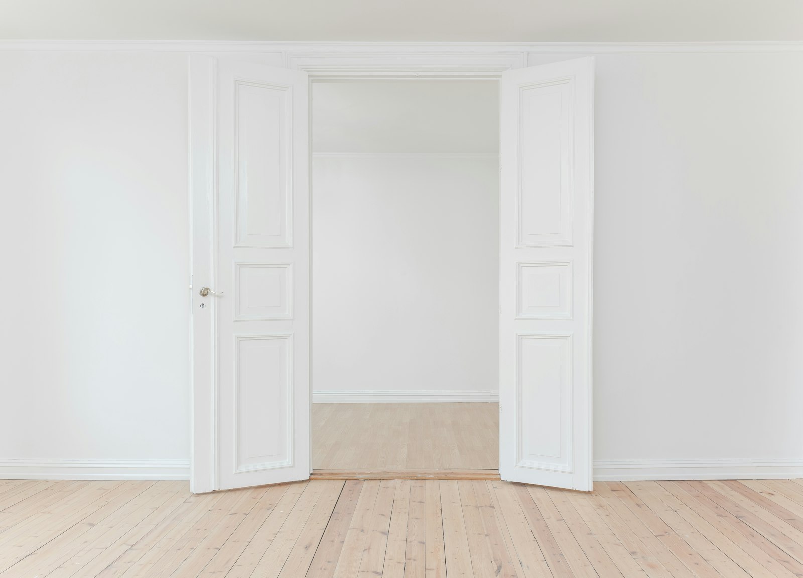 Open white double doors in an empty room