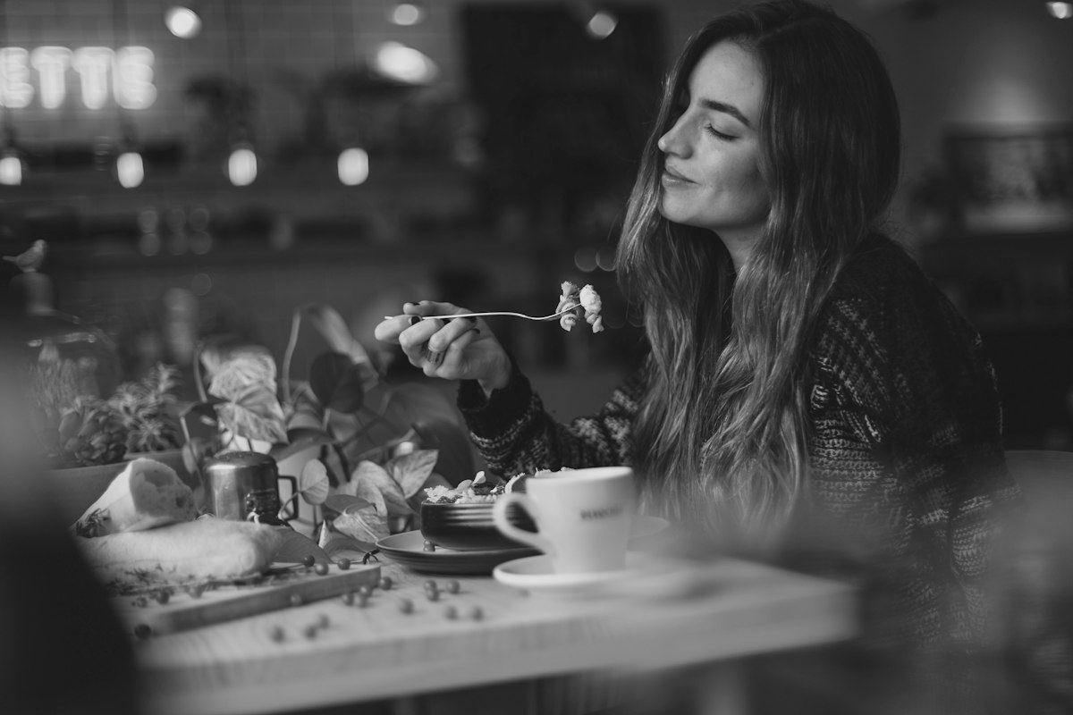 Woman tasting food at a cafe table