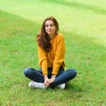 Woman in yellow sweater sitting on grass