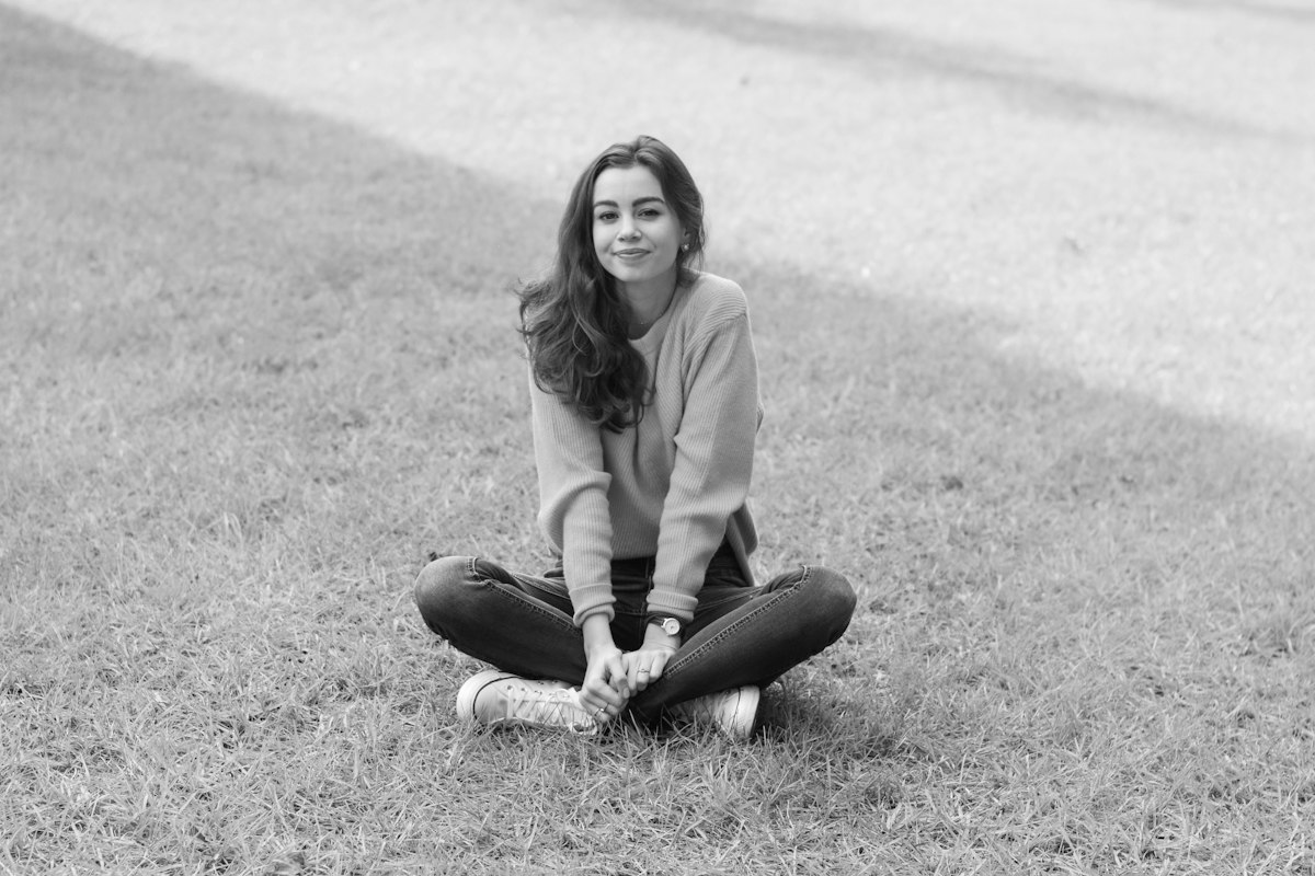 Woman in yellow sweater sitting on grass