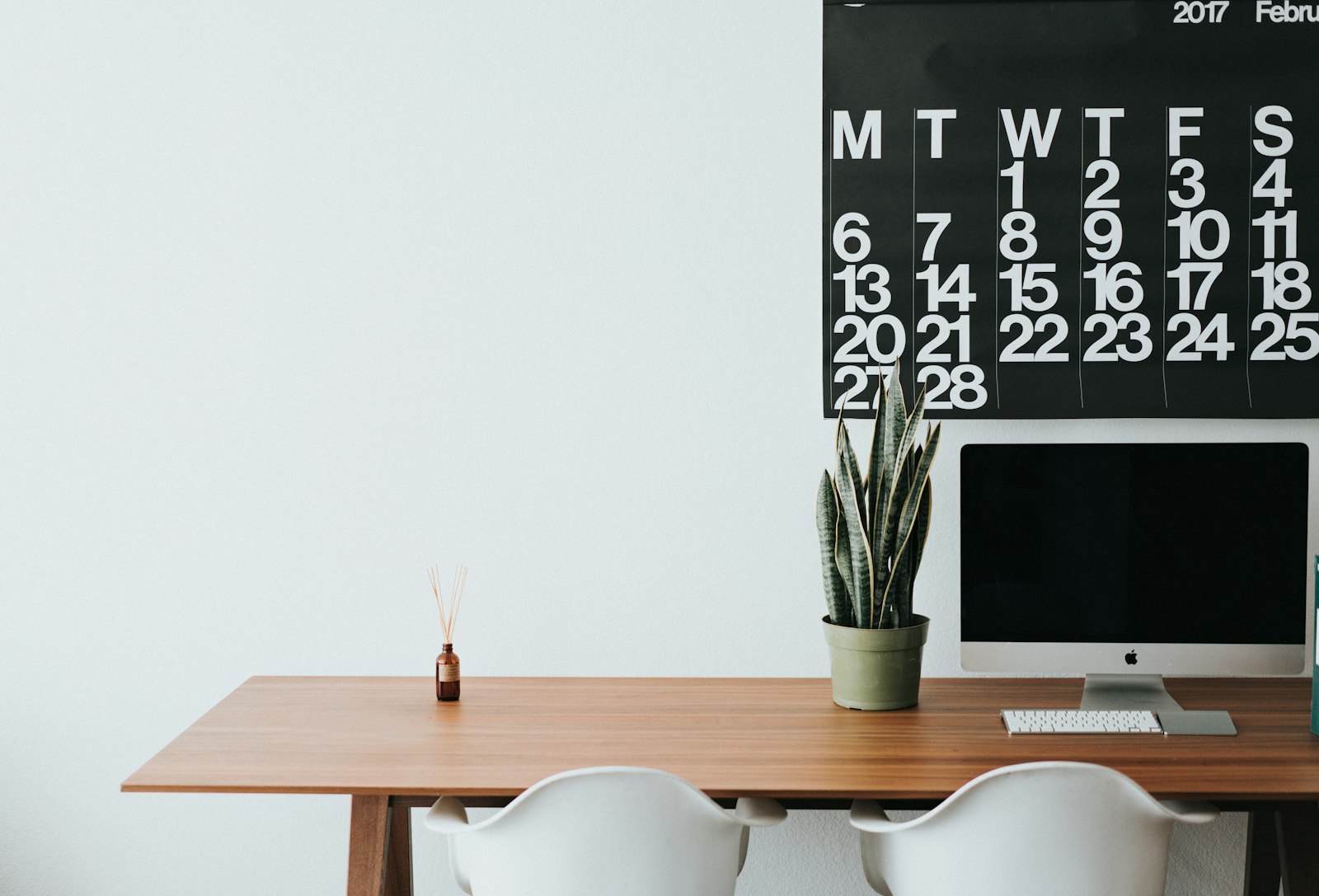 Wooden desk with monitor and wall calendar